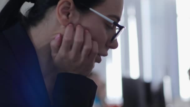 Beledigd meisje maakt gebruik van een smartphone op de werkplek zitten in het kantoor op een wazig achtergrond — Stockvideo