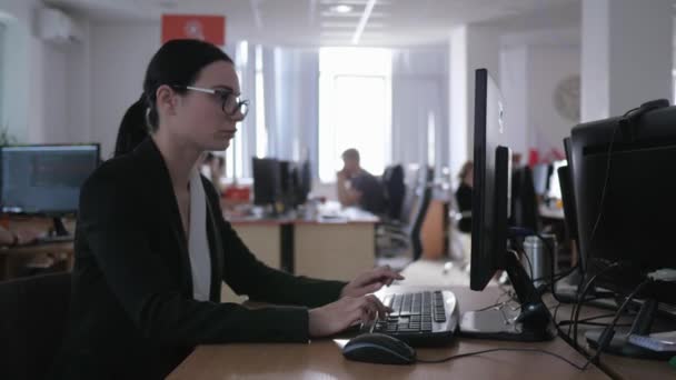 Σκληρή δουλειά γραφείου, απογοητευμένη επιχειρηματική κοπέλα με γυαλιά χρησιμοποιεί υπολογιστή και κρατά σημειώσεις — Αρχείο Βίντεο
