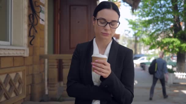 Пенсійна молода бізнес-леді гуляє по міських вулицях і п'є каву — стокове відео