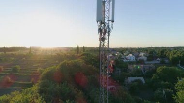 Telekomünikasyon kulesi, cep telefonu antenine insansız hava aracı görüntüsü güvenlik yeleği ve başlık takmış bir adam.