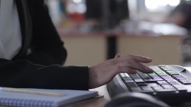 Mujer nerviosa escribiendo en un teclado de ordenador sentado detrás de un lugar de trabajo en la oficina de cerca — Vídeos de Stock