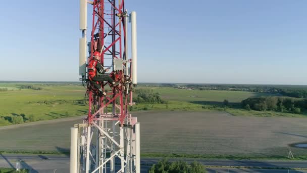 Drönare flyger runt utomhus repeater bas station torn, entreprenör arbetar på telekommunikation antenn system — Stockvideo