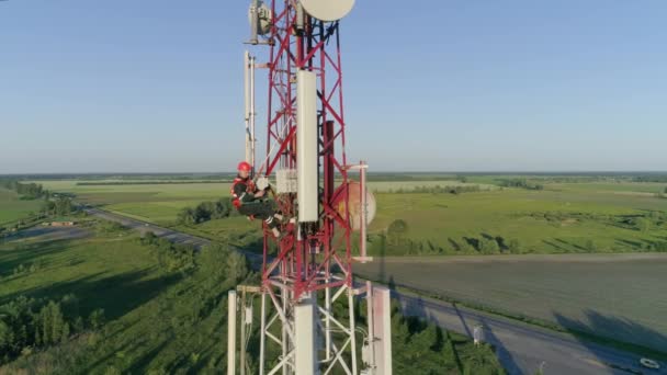 Techniker arbeitet bei gefährlichen Job verwendet Gadget auf Mobilfunk-Antenne, Drohne fliegt um Outdoor-Repeater-Basisstation — Stockvideo