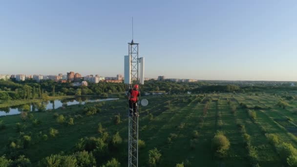 Κεραία πύργος επικοινωνίας, εναέρια άποψη του ανθρώπου λειτουργεί στο ύψος χρησιμοποιώντας εξοπλισμό ασφαλείας στο φόντο του ηλιοβασιλέματος — Αρχείο Βίντεο