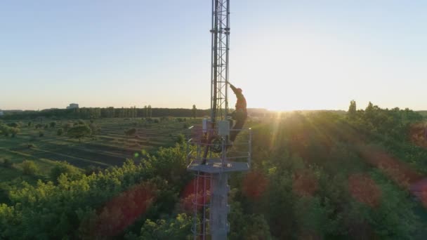 Nadmořská výška práce na mobilní anténě, muž v helmě zvedne ruce pro radost, když úspěšně odvedl svou práci na rádiové telekomunikační věži — Stock video