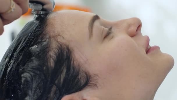 Салон красоты, мытье головы клиента в раковине под душем в парикмахерской — стоковое видео
