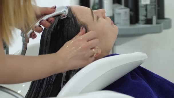 Higiene feminina, cabeleireiro lava o cabelo do cliente na pia no salão de beleza — Vídeo de Stock