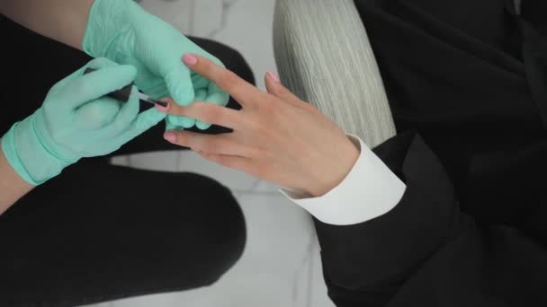 Lastik eldivenli profesyonel manikürcü güzellik salonunda kadına manikür yapıyor. — Stok video