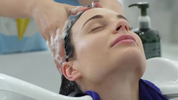 Cabeça de lavagem, mulher desfrutar de massagem cabeleireiro enquanto shampooing cabelo no salão de beleza — Vídeo de Stock