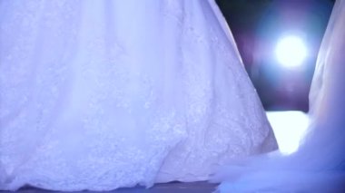 Gelinliklerin sunumu, podyumda beyaz önlüklü manken moda haftasında spot ışıklarıyla