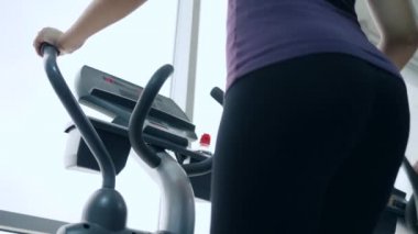 Güzel vücut, siyah taytlı kadın spor simülatöründe yakın plan spor salonunda.