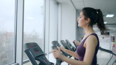 Kardiyo eğitimi, büyük pencereli spor salonunda spor yapan genç kadınlar.