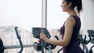 Spor salonunda spor yaparken kadın plastik şişeden maden suyu içer.