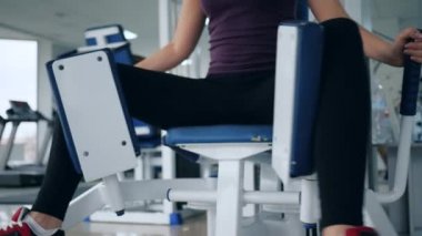 Kiz spor kulübünde otururken bacaklarini uzatarak egzersiz yapiyor.