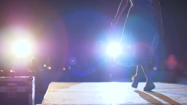 Дефиле, модель в стильной одежде идет по подиуму при освещении ярким прожектором — стоковое видео