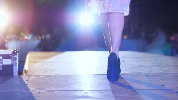 Presentazione della nuova collezione abiti alla moda, modello professionale con tacchi alti va lungo passerella in illuminazione riflettori alla settimana della moda — Video Stock