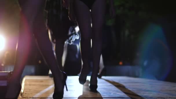 Pernas finas de modelos em sapatos pretos em saltos altos ir em linha ao longo da passarela no desfile de moda — Vídeo de Stock