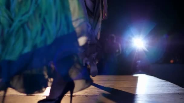 Défilé de mode, mannequin fille en mousseline de soie robe et chaussures élégantes descend podium dans les projecteurs lumineux — Video