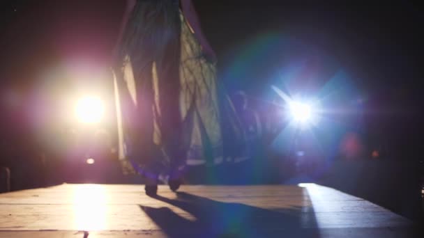Modèle en robe à la mode et chaussures en talons hauts marchant sur le podium en contre-jour gros plan — Video