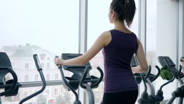 Cardio workout, attractive female does exercises on sport equipment in gym with panoramic windows — Stock Video