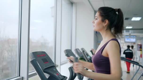 Egészséges életmód, sportnő épít izmok segítségével Elliptical edzők fitness klub — Stock videók