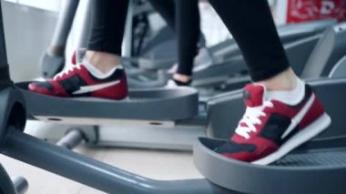 İnsanlar spor kompleksindeki eliptik spor eğitmenleri üzerinde egzersiz yapıyorlar.