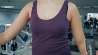 Spor salonundaki eliptik spor ayakkabıların üzerinde gülümseyen kadın portresi.