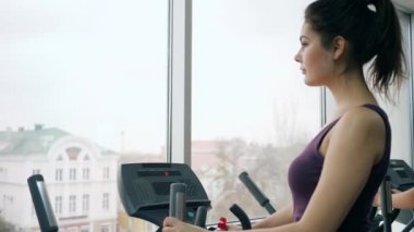 Beden eğitimine susamış bir kız spor simülatöründe koşuyor ve şişeden su içiyor.