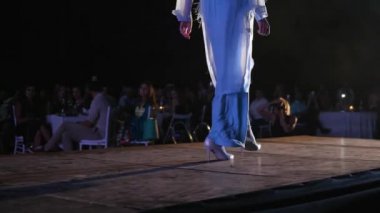 Şık uzun elbiseli ve topuklu ayakkabılı podyum mankenleri moda gösterisinde podyuma çıkıyorlar.