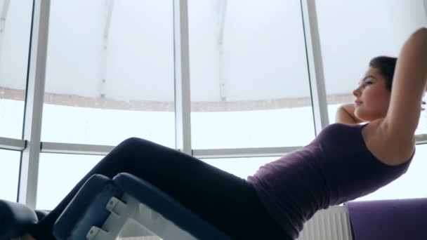 Ochtend oefening, meisje is schommelen pers in fitness club tegen van venster — Stockvideo