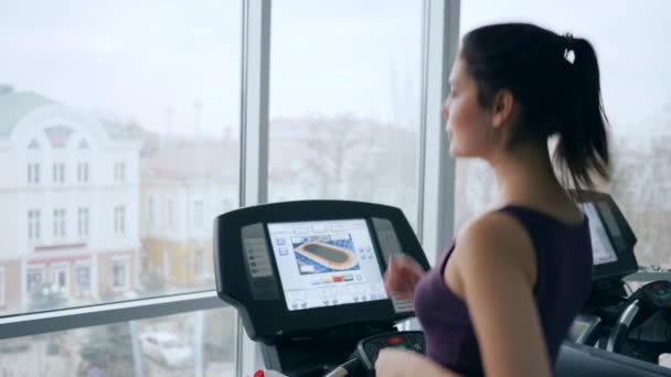 Morgonträning, glad tjej på löpband dricker mineralvatten från plastflaska i gymmet — Stockvideo
