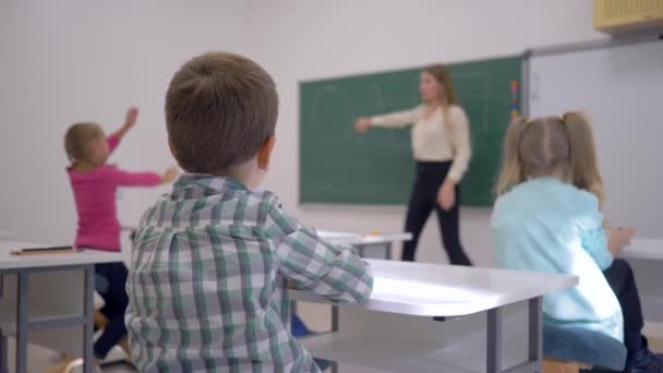 Educación de los niños, escolares en la lección escuchar al maestro en pizarra en centrado en el aula de la escuela — Vídeo de stock