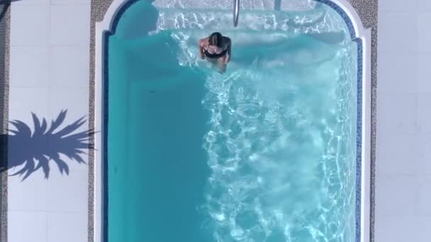 Formschöne Frau im Badeanzug schwimmt am Sommerwochenende im blauen Pool — Stockvideo