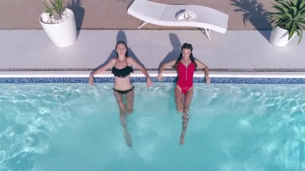 Beautiful girlfriends into bathing suit spend leisure in blue Poolside on summer weekend — Stock Video