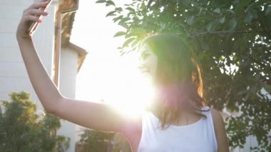 Mutlu çekici kadınlar akıllı telefonda fotoğraf çekiyorlar. Parlak güneş ışığında doğada.
