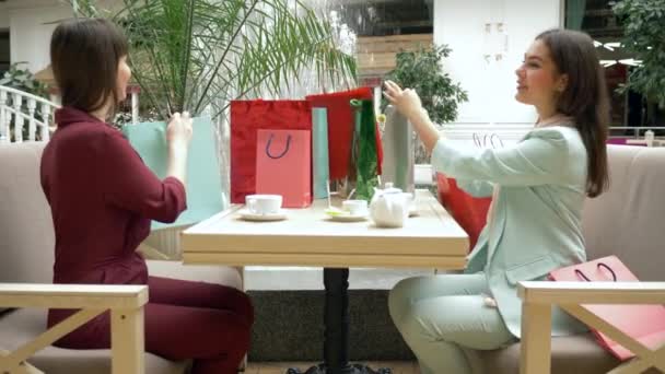 Shopping dag, glada kvinnor dricker te i restaurang skryta om inköp i säsongsförsäljning och rabatter på svart fredag i centrum — Stockvideo