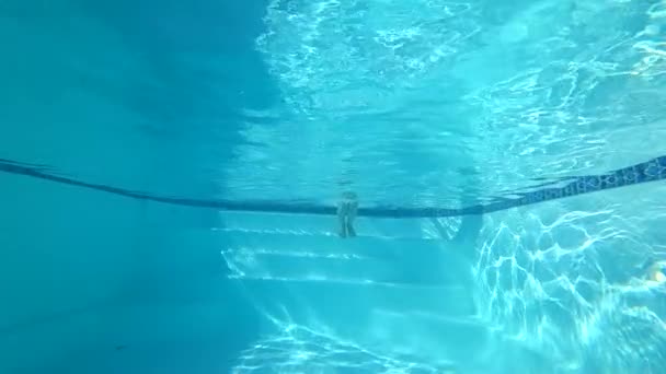 在水下游泳，女孩跳进游泳池里，睁大眼睛在清澈的水中漂流 — 图库视频影像