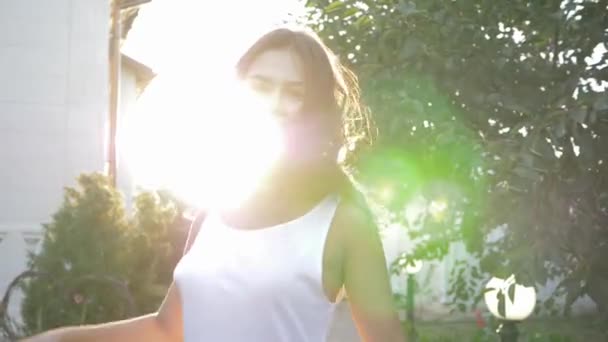 Joyful laughing woman turns and waves hair in bright sunrays outdoors — Stock Video