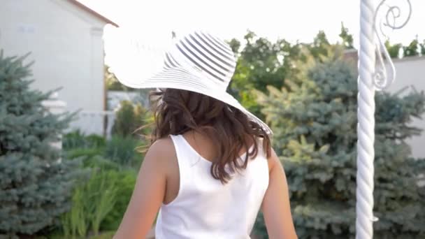 Usmívající se mladá žena do klobouku se širokým okrajem přitahuje k sobě a běží napřed — Stock video