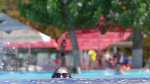 Retrato de chica sonriente en gafas de sol descansando en la piscina azul de verano — Vídeo de stock