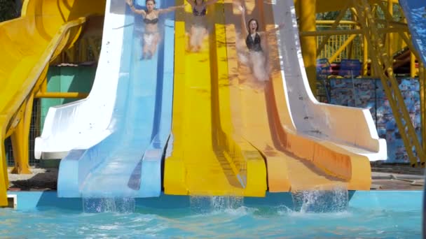 Divertimento estivo al parco acquatico, ragazze coraggiose che scivolano giù sugli scivoli e si tuffano in piscina con Splashing — Video Stock