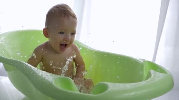 Baby bathing, smiling little child boy is played water while taking bath — Stock Video