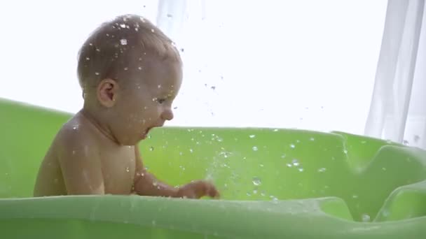 Cute small child boy relish splashing water while taking bath — Stock Video