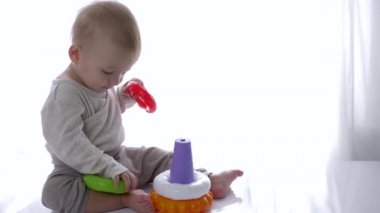 Küçük sevimli çocuk parlak odada eğitici oyuncaklar piramidi oynadı.