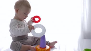 Gülümseyen güzel bebek içeride eğitici oyuncaklar piramidi oynadı.