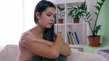Kadın depresyonu, ruhsal bozukluklara aldırış etmeyen üzgün kız evdeki parlak odada koltukta oturuyor.