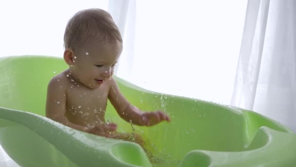 Körperpflege, netter kleiner Junge, der Spaß beim Wasserspritzen hat, während er baden geht — Stockvideo