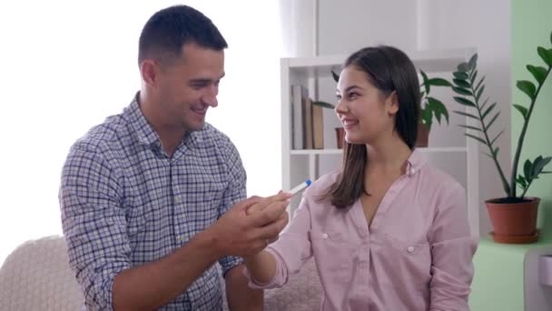 Fertility woman with spouse with pregnancy test rejoices expecting baby and happily hugging each other indoors at home — Stock Video