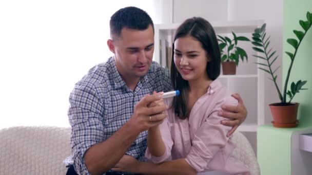 Familia sana pareja con prueba de embarazo feliz con resultado positivo y felizmente abrazándose en la habitación en casa — Vídeo de stock