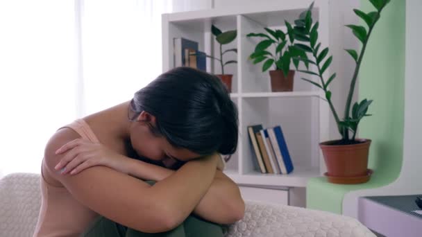 Kvinna melankolisk, upprörd kvinna i depression sitter på soffan i ljusa rum hemma — Stockvideo